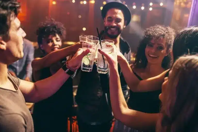 Five friends toasting drinks at a warm, festive indoor party.