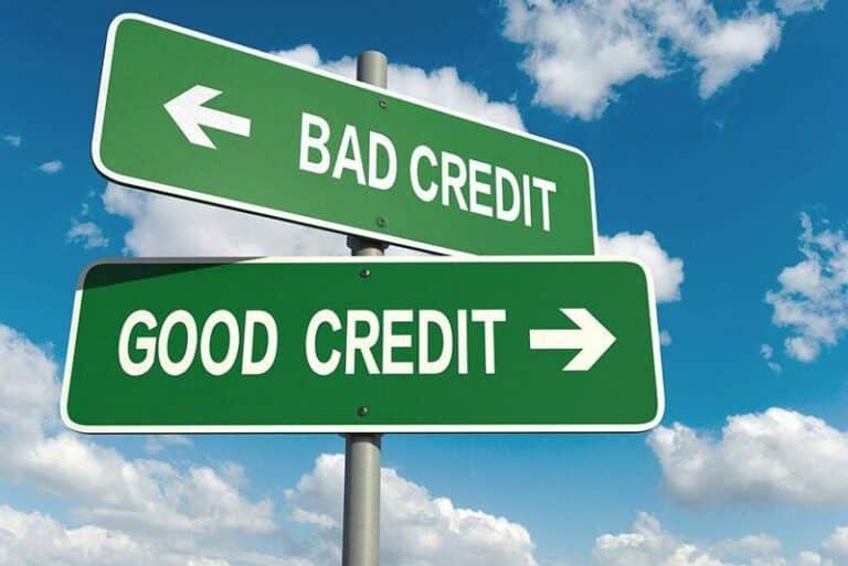 Green street signs point left to bad credit, right to good credit, blue sky behind.
