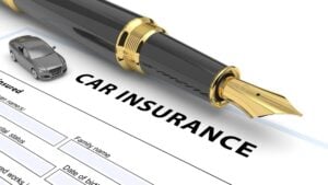 Fountain pen and toy car atop a blank car insurance form.