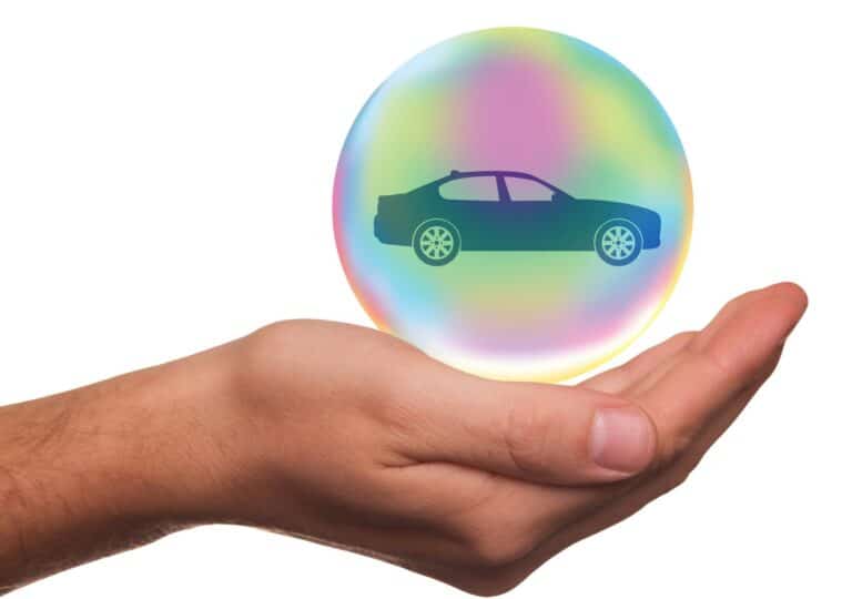 Hand holds colorful bubble with car icon, white background.