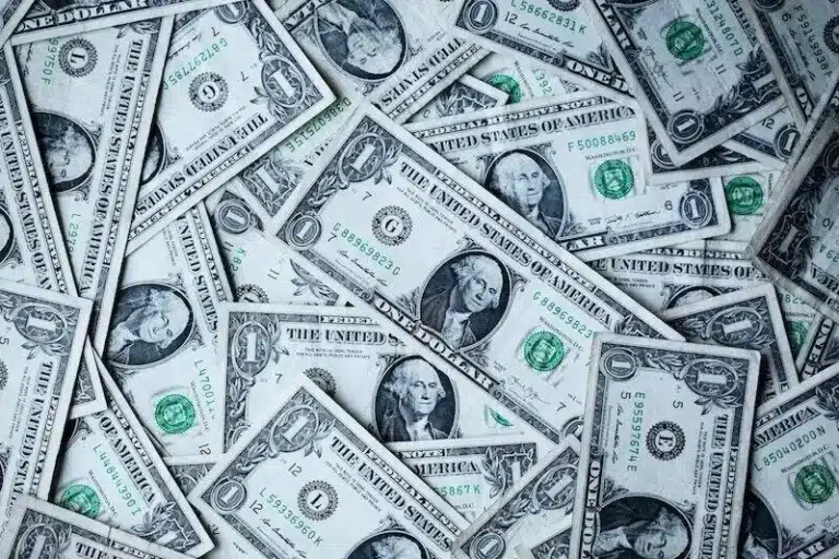 Overlapping U.S. one-dollar bills scattered in a messy pile.