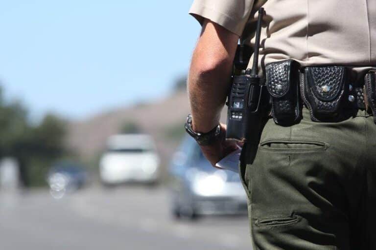 Police officer watches traffic by highway on clear day.