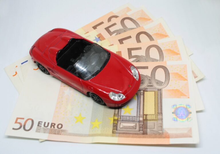 Red toy car sitting on 50 euro bills, white background. Red toy car sitting on 50 euro bills, white background.